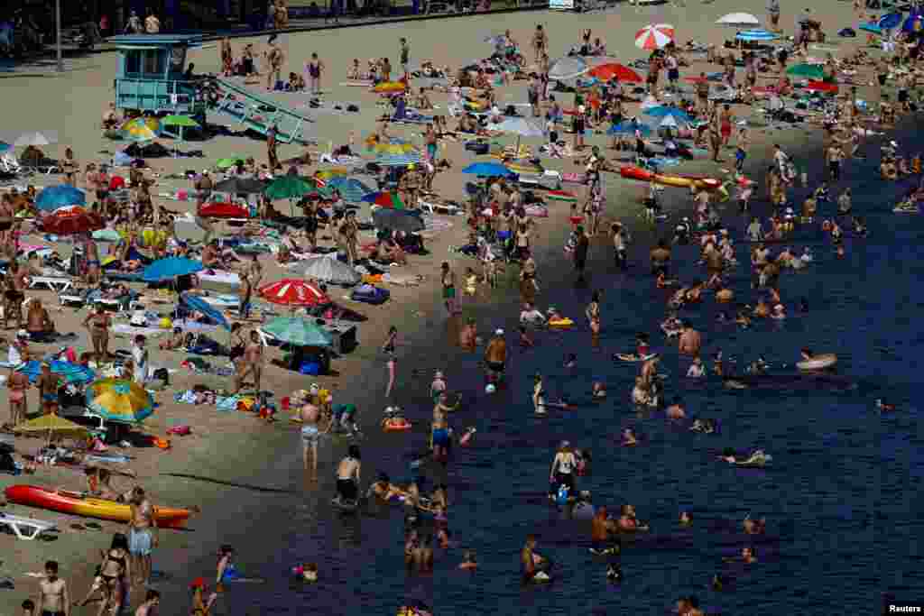 People rest at a city beach on the bank of the Dnipro River on an extremely hot summer day, amid Russia&#39;s attack on Ukraine, in Kyiv, Ukraine.