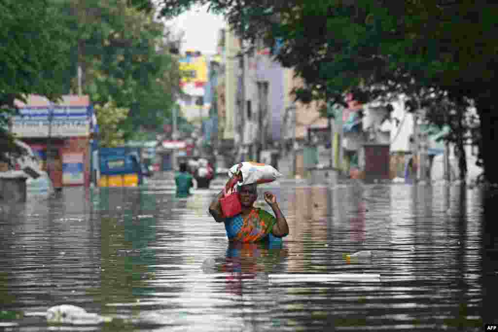 A woman along with her belongings, wades through a flooded street after heavy rains in Chennai, India.&nbsp;Chest-high water surged down the streets of Chennai with eight people killed in intense floods as Cyclone Michaung made landfall on the southeast coast.&nbsp;