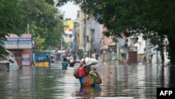 A woman along with her belongings, wades through a flooded street after heavy rains in Chennai, India.&nbsp;Chest-high water surged down the streets of Chennai with eight people killed in intense floods as Cyclone Michaung made landfall on the southeast coast.&nbsp;