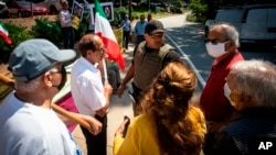 FILE - Demonstrators speak with a member of the Fulton County Sheriff's Office in front of a polling place for Iranian Americans taking part in Iran's presidential elections on June 18, 2021, in Sandy Springs, Georgia.
