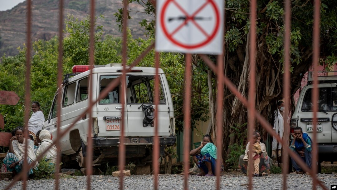FILE - An ambulance said by residents to have been damaged and stripped for parts by Eritrean soldiers sits next to people as they wait to be seen at a medical clinic in Abi Adi, in the Tigray region of northern Ethiopia, May 11, 2021.
