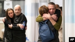 Hostages Fernando Marman, right, and Louis Har, second from left, hug relatives after being rescued from captivity in the Gaza Strip, at the Sheba Medical Center in Ramat Gan, Israel, Feb. 12, 2024.