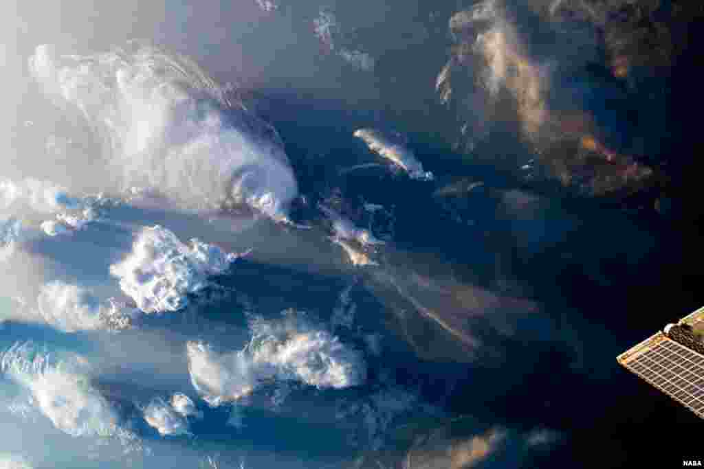 As the International Space Station orbited 259 miles above North Africa, clouds covered the sky, in this image taken July 13, 2023, released by NASA. To the bottom right of the image, one of the station's roll-out solar arrays peeks through.