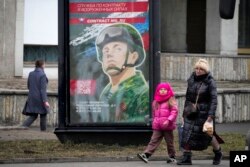 People walk past an army recruitment billboard with the words "Military service under contract in the armed forces," in St. Petersburg, Russia, March 24, 2023.