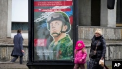 People walk past an army recruitment billboard with the words "Military service under contract in the armed forces," in St. Petersburg, Russia, March 24, 2023.