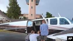 FILE: People look inside a plane at the Welkom Airport, in Welkom, South Africa, for a venomous snake seen under pilot Rudolf Erasmus's seat midair, Monday April 3, 2023. Erasmus was flying the light aircraft when he felt “something cold” slide across his lower back.