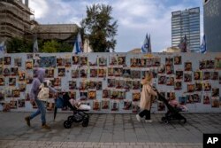 People walk past a wall with photographs of hostages, mostly Israeli civilians who were abducted during the Oct. 7 Hamas attack on Israel, in Tel Aviv, Israel, Jan. 31, 2024.
