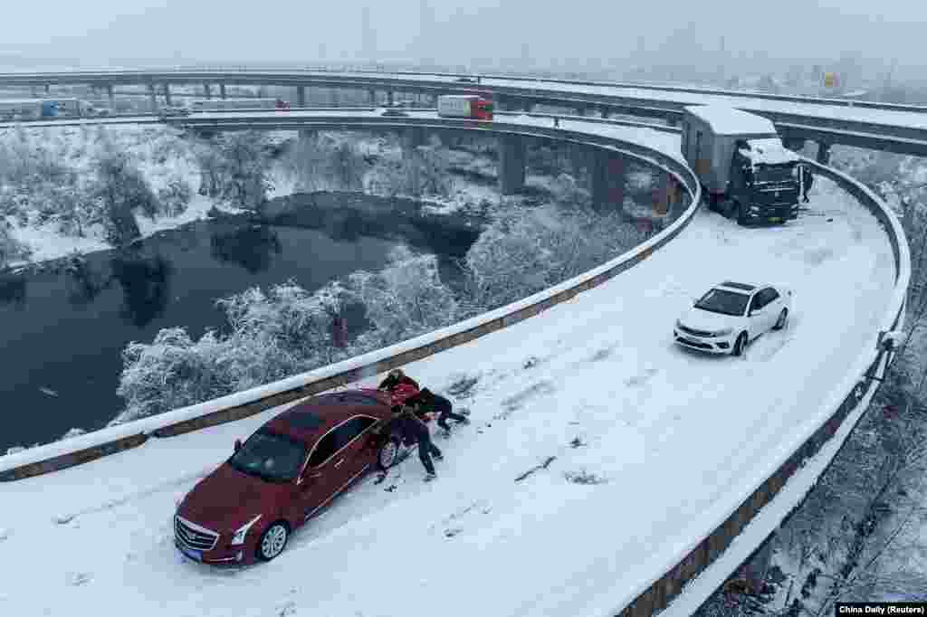 People push a car stuck on a highway following heavy snowfall in Wuhan, Hubei province, during the Spring Festival travel rush ahead of the Chinese Lunar New Year, Feb. 6, 2024.