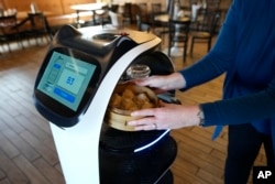 A customer receives a meal delivered by a robot at the Noodle Topia restaurant on March 20, 2023 in Michigan. (AP Photo/Carlos Osorio)