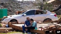 FILE - Charles Shields, left, sits with friend Robbie Diffey on the roof of Diffey's garage after a tornado destroyed her home, March 27, 2023, in Rolling Fork, Miss. President Joe Biden on Friday will visit the town.