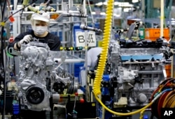 Seorang pekerja di Nissan Motor Co. mengecek mesin di sebuah jalur perakitan di pabriknya di Yokohama, dekat Tokyo, 2 Agustus 2017. (Foto: Shizuo Kambayashi/AP Photo)