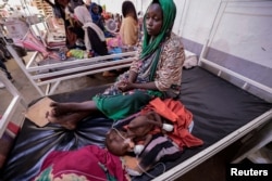 Fadila Ahmad, a Sudanese woman who fled the conflict in Geneina, in Sudan's Darfur region, sits beside her child Abd el salam Yakoub Bakr, who is suffering from malnutrition at Medecins Sans Frontieres (MSF) mission hospital in Adre, Chad, July 24, 2023.