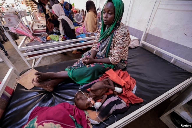 Fadila Ahmad, a Sudanese woman who fled the conflict in Geneina, in Sudan's Darfur region, sits beside her child Abd el salam Yakoub Bakr, who is suffering from malnutrition at Medecins Sans Frontieres (MSF) mission hospital in Adre, Chad, July 24, 2023.