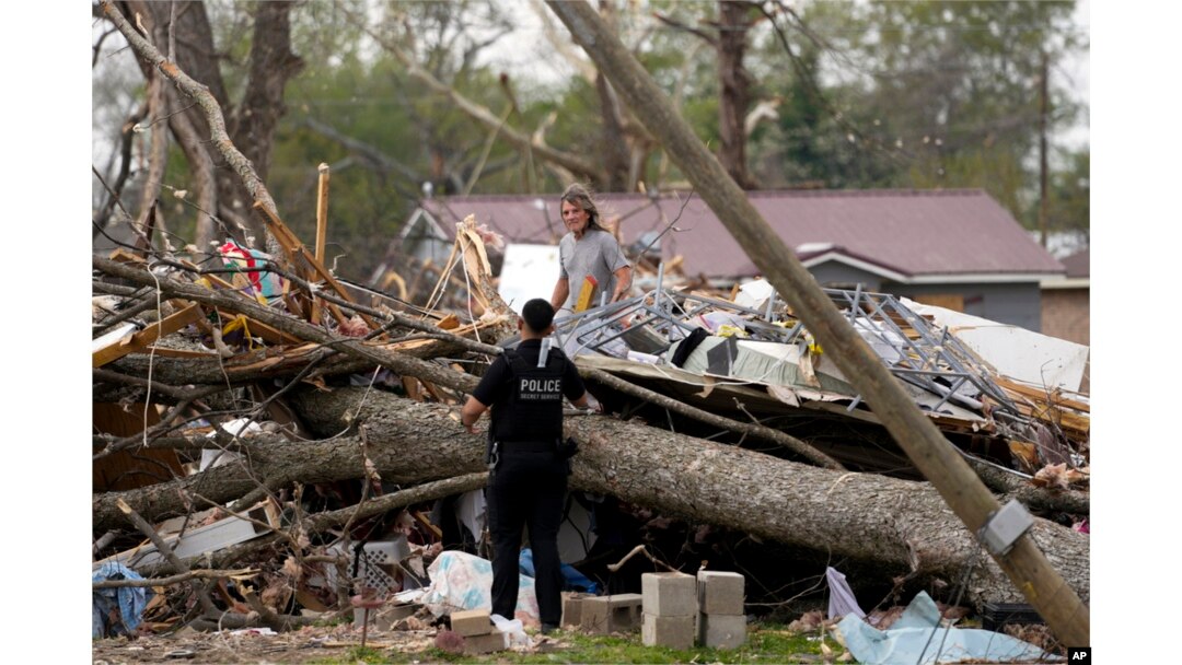 A uniformed U.S. Secret Service police officer talks to a person digging through debris as President Joe Biden approaches the area in Rolling Fork, Mississippi, March 31, 2023.