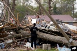 A uniformed U.S. Secret Service police officer talks to a person digging through debris as President Joe Biden approaches the area in Rolling Fork, Mississippi, March 31, 2023.