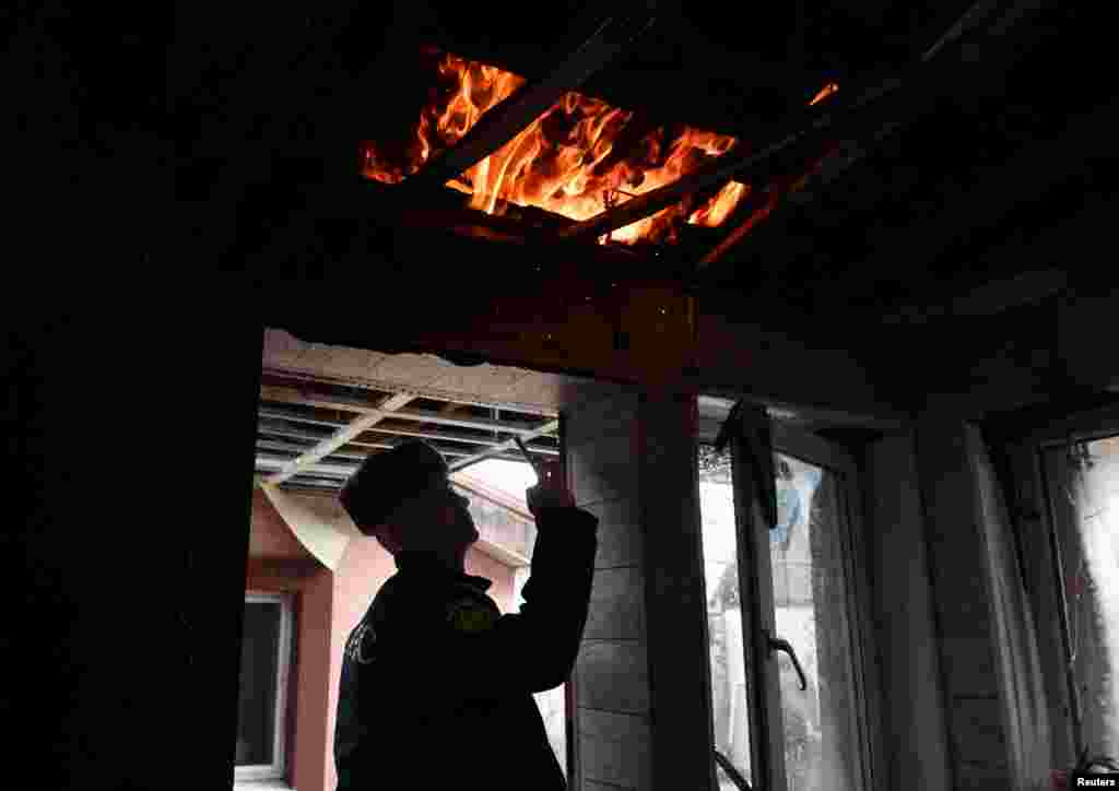 Спасувач фотографира внатре во оштетена станбена зграда погодена од неодамнешното гранатирање во текот на руско-украинскиот конфликт во Доњецк, Украина под руска контрола.