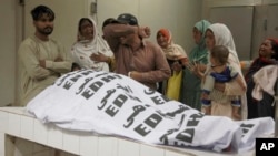 People mourn next to the body of a relative who was killed in a stampede at a Ramadan food distribution center in Karachi, Pakistan, March 31, 2023.