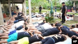 In this photo released by Indonesian authorities, foreign nationals detained on allegations of conducting cybercrime and visa violations are lined up on the ground following a raid on a villa in Tabanan, Bali, Indonesia, June 26, 2024.