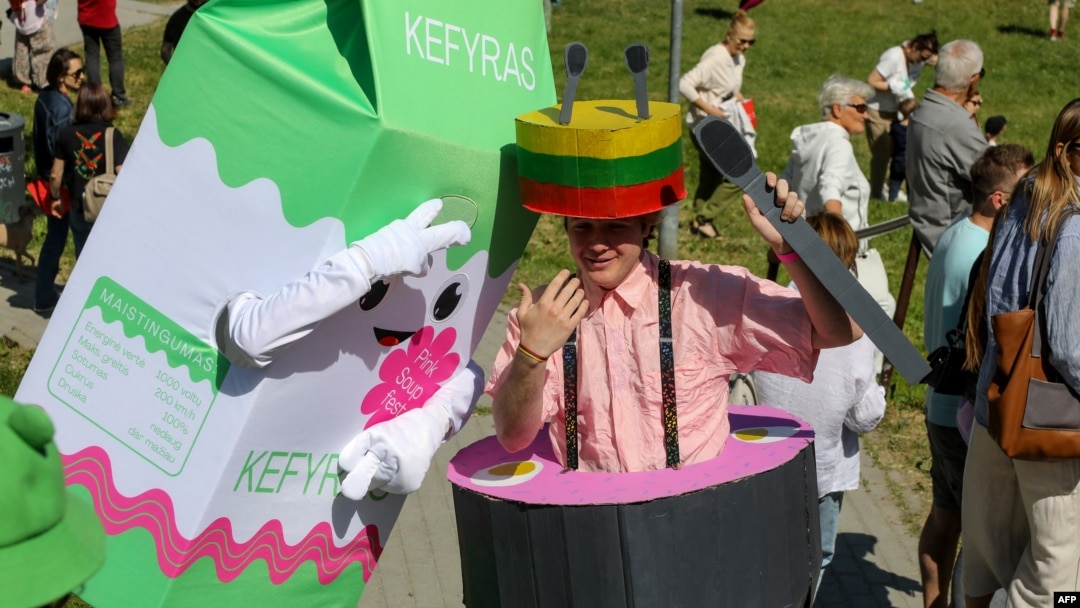 Participants dressed as Saltibarsciai soup take part in the Saltibarsciai Slip and Slide competition during the Pink Soup Fest in Vilnius on June 10, 2023.