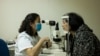 资料照：北京同仁医院的一名眼科医生为病人检查眼睛。（2014年10月8日）