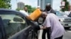 FILE - A man buys black market fuel in Lagos, Nigeria, May 30, 2023. Fuel prices soared in Nigeria last year after President Bola Tinubu ended subsidies that had kept prices low for many years.