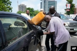FILE - A man buys black market fuel in Lagos, Nigeria, May 30, 2023. President Bola Tinubu has scrapped a decadeslong government-funded subsidy, leading to long lines at fuel stations as drivers scrambled to stock up before costs rise.