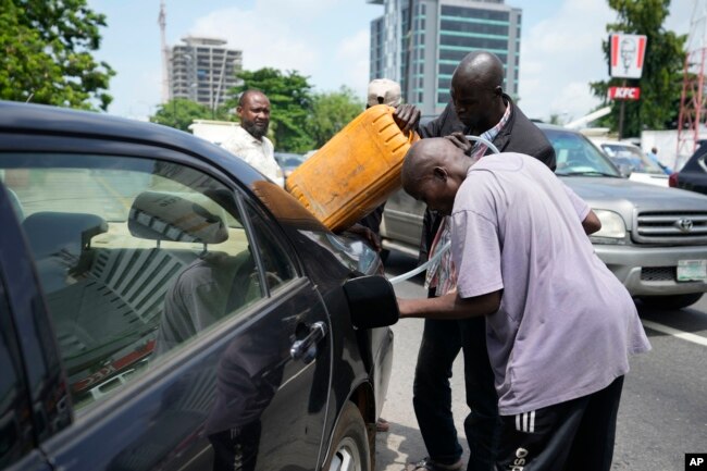 FILE - A man buys black market fuel in Lagos, Nigeria, May 30, 2023. President Bola Tinubu has scrapped a decadeslong government-funded subsidy, leading to long lines at fuel stations as drivers scrambled to stock up before costs rise.