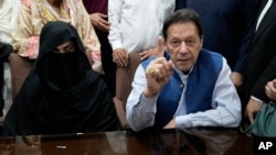FILE - Pakistan's former Prime Minister Imran Khan, right, and his wife, Bushra Bibi, speak to the media at a court in Lahore, Pakistan, July 17, 2023. A Pakistani court on Feb. 27, 2024, indicted Khan, already serving a prison sentence, and his wife in a corruption case.