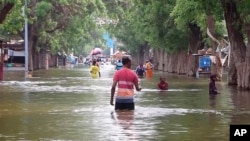 In this image from video, residents move through floodwaters in the town of Beledweyne, Somalia, Nov. 19, 2023. 