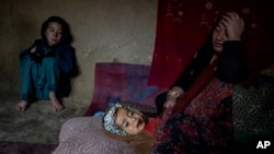 An internally displaced woman takes care of her sick child in a camp on the outskirts of Kabul, Afghanistan, Thursday, Feb. 9, 2023. She has no money to treat her sick child. (AP Photo/Ebrahim Noroozi)