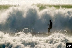 A surfer catches waves at Topanga State Beach in Los Angeles, Dec. 28, 2023.