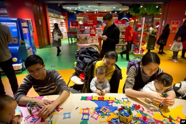 In this Dec. 23, 2017 photo, parents and children play together at an activity station during the grand opening of a Hamleys toy store in Beijing. (AP Photo/Mark Schiefelbein)