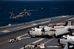 U.S. Navy MH-60S Hawk helicopter, left, and C-2 Grayhound are seen on the flight deck of the USS Nimitz off the coast of Busan, South Korea, Monday, March 27, 2023.