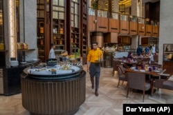 Priyesh Shinde carries Veen bottled water before serving it to customers at the Conrad Hilton hotel in Pune, India, Thursday, May 4, 2023. Veen, a fine water bottled in Bhutan, is primarily sold in luxury restaurants and hotels in India. (AP Photo/Dar Yasin)