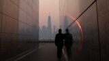 A man stands in the Empty Sky 911 Memorial in Jersey City, N.J., looking toward the One World Trade Center tower in New York City shortly after sunrise as haze and smoke caused by wildfires in Canada hangs over the Manhattan skyline, June 8, 2023. 