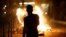 A person stands near a burning container as people protest following the death of Nahel, a 17-year-old teenager killed by a French police officer in Nanterre during a traffic stop, and against police violence, in Paris, France, June 30, 2023. 