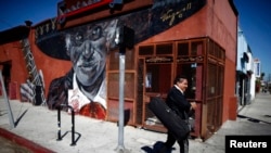 Mariachi camina junto a un mural en la zona de Boyle Heights de Los Ángeles,