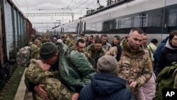 A Ukrainian woman soldier, left, kisses her husband as they meet at a railway station close to the frontline in Kramatorsk, Donetsk region.