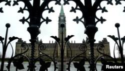 FILE - The Canadian Parliament building is framed through a gate on Parliament Hill in Ottawa, Ontario.
