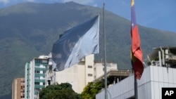 U.N. and Venezuelan flags hang outside the building that houses part of the U.N. human rights office in Caracas, Venezuela, Feb. 15, 2024. Venezuela on Thursday ordered the agency to suspend operations, accusing it of promoting opposition to the country.