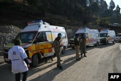 Sercurity personnel stand near ambulances on standby as an effort to free workers trapped in a collapsed road tunnel enters its final phase, in the Uttarkashi district of India's Uttarakhand state, Nov. 23, 2023.