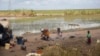 FILE - A woman cooks in a displacement camp on the bank of a flooded rice paddy near the village of Nicoadala, Zambezia province, Mozambique, March 24, 2023. Weeks after a cyclone hit Mozambique twice, the still-flooded country faces a cholera outbreak.