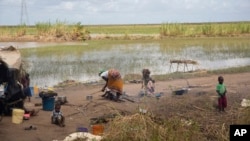 FILE - A woman cooks in a displacement camp on the bank of a flooded rice paddy near the village of Nicoadala, Zambezia province, Mozambique, March 24, 2023. Weeks after a cyclone hit Mozambique twice, the still-flooded country faces a cholera outbreak.