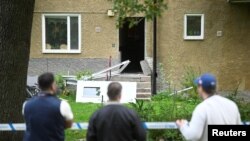 Orang-orang mengamati gedung yang ditutup dengan garis polisi menyusul ledakan di Hasselby, Stockholm, Swedia, 26 September 2023. (Fredrik Sandberg/TT News Agency/via REUTERS)