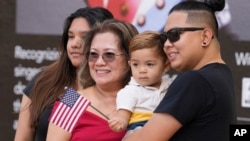 FILE - Rita Guevara of the Philippines, center, takes a photo with her family following a naturalization ceremony, Sept. 15, 2023, in Miami. (AP Photo/Marta Lavandier)