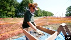 Volunteer Nancy Carlson sifts through dirt as part of the search suspected remains of children who once attended the Genoa Indian Industrial School, July 10, 2023, in Genoa, Neb.