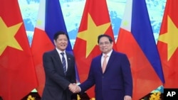 Presiden Filipina Ferdinand Marcos Jr. (kiri) dan Perdana Menteri Vietnam Pham Minh Chinh berjabat tangan dalam pertemuan di Hanoi, Vietnam, pada 30 Januari 2024. (Foto: Hoang Thong Nhat/VNA via AP)