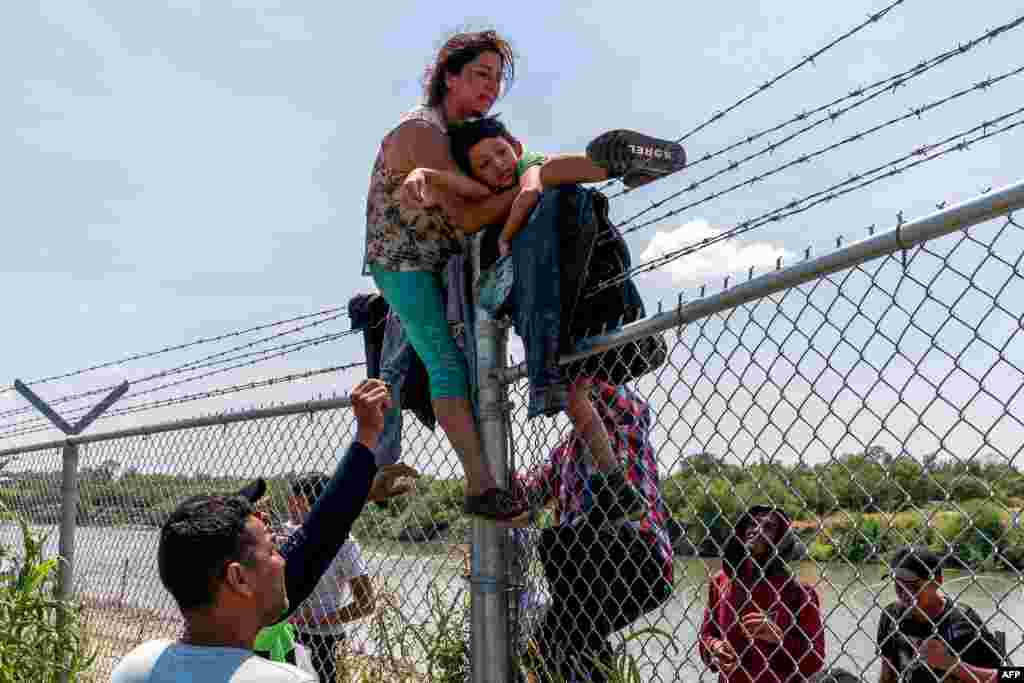 Migrants climb over a barbed wire fence after crossing the Rio Grande into U.S. from Mexico, in Eagle Pass, Texas, Aug. 25, 2023.