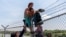 FILE - Migrants climb over a barbed wire fence after crossing the Rio Grande into US from Mexico, in Eagle Pass, Texas, Aug. 25, 2023. 
