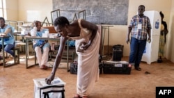 A voter casts her ballot at a polling station at Bwakya school in Lubumbashi, Dec. 21, 2023.